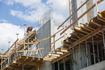 Construction site of an apartment block in progress. Raw state with scaffolding and concrete structures. Industrial background framework and building materials used. Urban development.