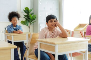 Diverse group of schoolchildren sitting at desks in a classroom, listening to a lesson.