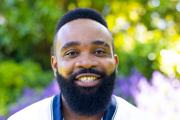 Smiling man with beard enjoying outdoor garden, looking at camera