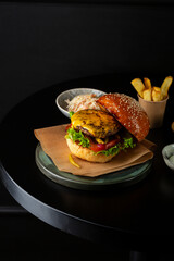 close up of burger with cheese and potatoes on a black table fast food