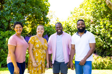 Smiling friends standing together outdoors, enjoying sunny day in park