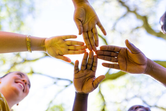 Joining hands together outdoors, friends showing unity and teamwork