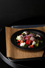 Greek salad on black plate food background