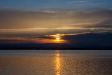 Sunset over a calm lake with the reflections of the last rays of sun on the water