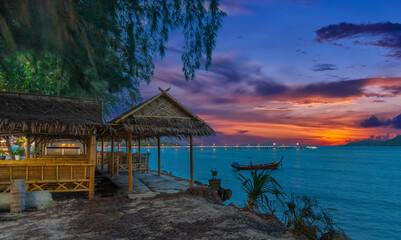 Colourful Skies Sunset over Rawai Beach in Phuket island Thailand. Lovely turquoise blue waters, lush green mountains colourful skies and beautiful views of long tail Boats