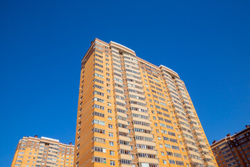 brown orange brick wall of multi-storey apartment building on blue sky. brick facade of panel high rise residential building