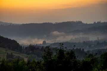 Mountain valley with mists illuminated by the setting sun