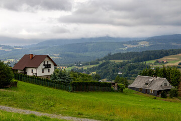 Obraz premium View of koniakow houses with misty hills in the background