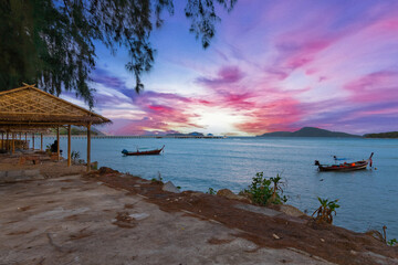 Colourful Skies Sunset over Rawai Beach in Phuket island Thailand. Lovely turquoise blue waters, lush green mountains colourful skies and beautiful views of long tail Boats