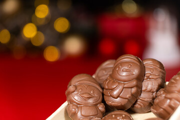 Chocolates in the shape of Christmas figures on the background of a flashing garland