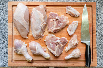 Top view of Raw chicken cuts and a knife on a wooden board © Kevin