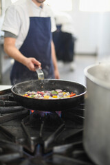 chef preparing vegetables in a pan