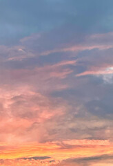 a light cloudy sky just before sunset shows a multi colored view of pink and orange