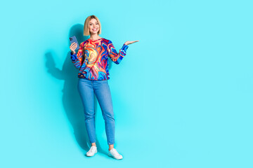 Full length photo of attractive girl dressed print shirt holding smartphone arm show object empty space isolated on blue color background