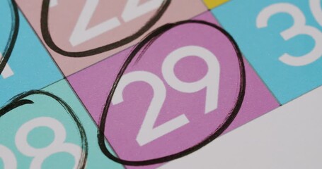 Close-up view of the number 29 circled on a colorful calendar with a black pen, signifying a marked date or important event. Close-Up of Number 29 Circled on Colorful Calendar with Black Pen