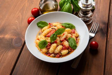 Deliziosi gnocchi di patate con pomodoro, basilico, olio di oliva e parmigiano, cibo italiano, dieta mediterranea 