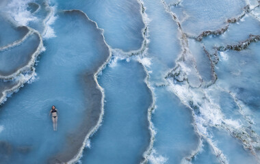 Aerial view of woman enjoying sunrise at Terme di Saturnia thermal springs, Tuscany, Italy.