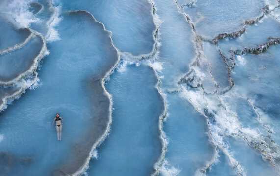 Aerial view of woman enjoying sunrise at Terme di Saturnia thermal springs, Tuscany, Italy.