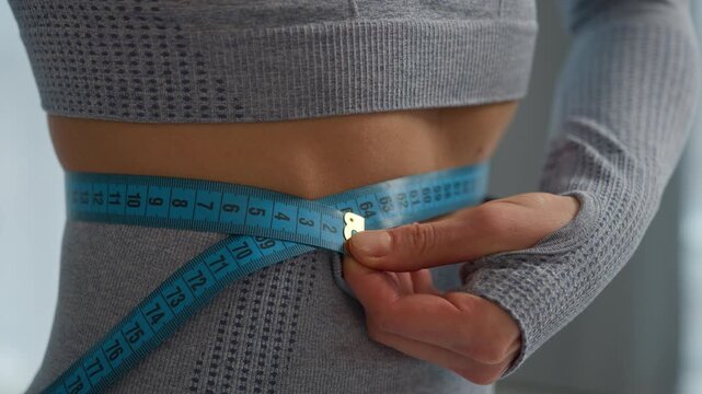 Close up slim slender woman sport girl measure waistline measuring tape achieve good result waist belly fit body shape figure size abdomen slimming health care weight loss diet healthy eat fitness gym