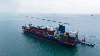 Aerial top view over international containers cargo ship at industrial import-export port prepare to load containers with big container loader ship vessel. global transportation and logistic business