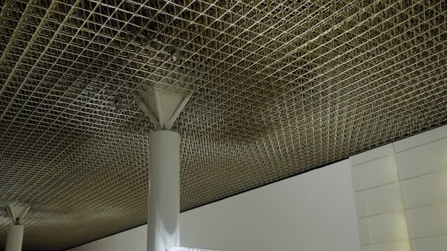 This image captures the sophisticated architectural design of a ceiling in a modern public building, showcasing the detailed work and contemporary style. Intricate Ceiling Design at a Public Facility