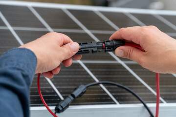 Close up of technician's hands connecting mc4 connectors over the solar panel.