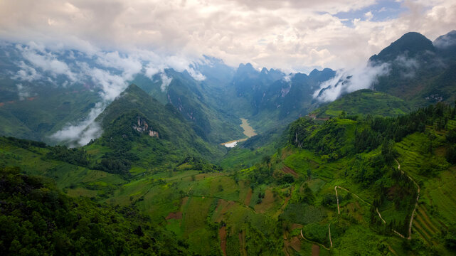 Aerial view of lush valley with misty mountains, nho que river, and remote forest, tu san cayon, ha giang, vietnam.
