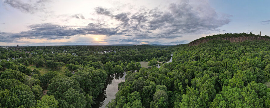 Aerial view of lush forest, river, cliff, and sky at East Rock Park, New Haven, Connecticut, United States.