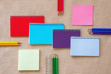 Different colorful spiral notepads. Various notes and colored pencils. Flat lay, copy space