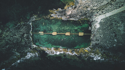 Qawra Pool on Malta's northern coast is a stunning natural sea pool carved into the rocky shoreline. Captured from above by drone, this picturesque location boasts crystal clear, turquoise waters set  © Tomasz