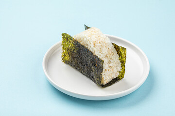 Portion of japanese onigiri snack on plate on blue background