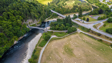 Aerial view of Craigellachie Bridge, river, forest, fields, and road, Moray, Scotland, United Kingdom.