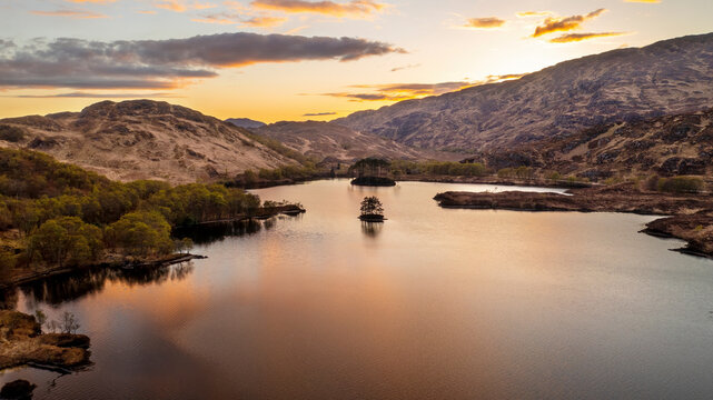 Aerial view of serene lake, mountains, and twilight reflection at Loch Eilt, Scotland.