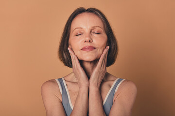 No filter photo of charming senior woman lifting cream facial procedure isolated on beige color...