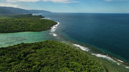 Aerial view of tropical coastline with lush forest, reef, and serene ocean, Xere, New Caledonia.