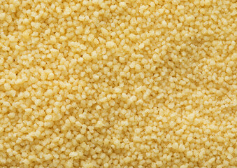 Yellow raw organic healthy couscous grain seeds textured background.Macro.