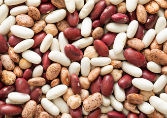 Assorted mix of red and white and variegated bean seeds with chickpeas textured background.Macro.
