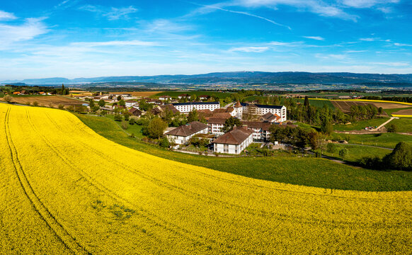 Aerial view of scenic Cistercian abbey surrounded by yellow and green fields, Frienisberg, Bern, Switzerland.