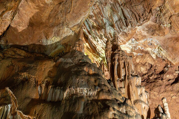 A cave with a lot of rock formations and a lot of stalactites. The cave is dark and the formations are very tall.