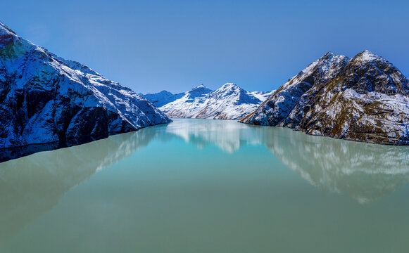Aerial view of serene alpine lake Grande Dixence with snow-capped mountains and pristine water, Valais, Switzerland. - Powered by Adobe