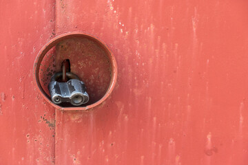 An old padlock on an iron door is protected from burglary and bad weather by a piece of pipe....