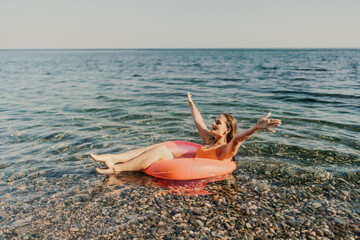 A woman is floating on a red inflatable raft in the ocean
