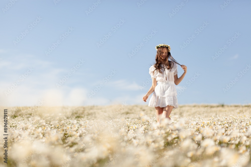 Poster beautiful girl with chamomile flowers walking in field