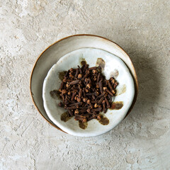 ceramic bowl with dried cloves on a light table