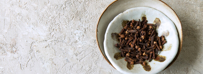 ceramic bowl with cloves on a light table, space for text