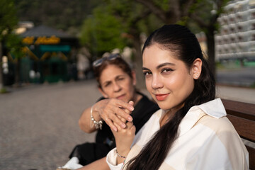 Madre e hija están sentadas y juegan con las manos.
