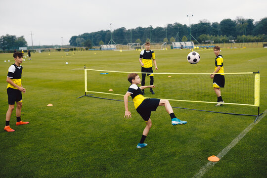 Youth soccer players playing football tennis training game. Happy teenage soccer players playing football tennis on training session. Teenagers practicing soccer on grass pitch.