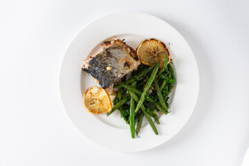 Savor the wholesome flavors of baked green beans with onions and baked mackerel, elegantly plated on a white background, ideal for a nutritious and flavorful dinner or lunch