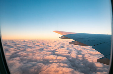 Airplane wing view over sunset clouds during flight