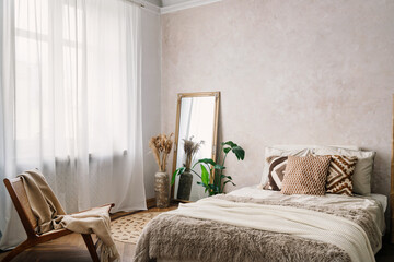 Bohemian bedroom with comfort bed, chair and mirror in room © brizmaker